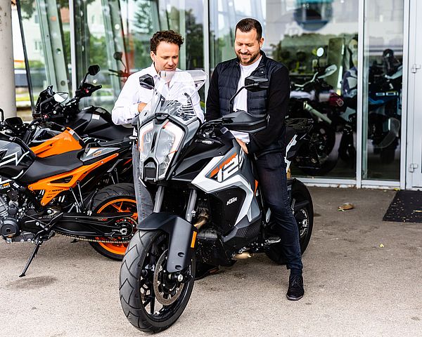 Mann mit dunklen Haaren und Lederjacke sitzt auf Motorrad.